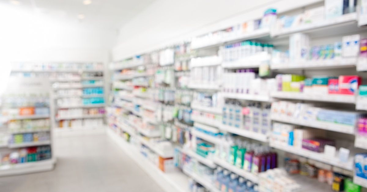 A blurry view of the inside of a pharmacy. The pharmacy is well-stocked with inventory and there are no workers.