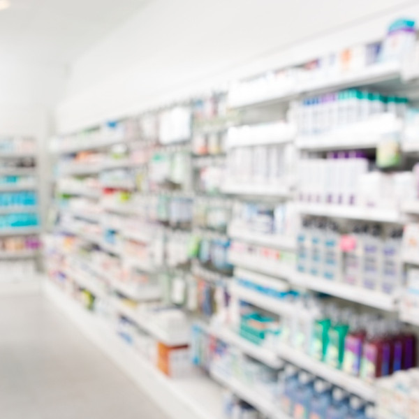 A blurry view of the inside of a pharmacy. The pharmacy is well-stocked with inventory and there are no workers.