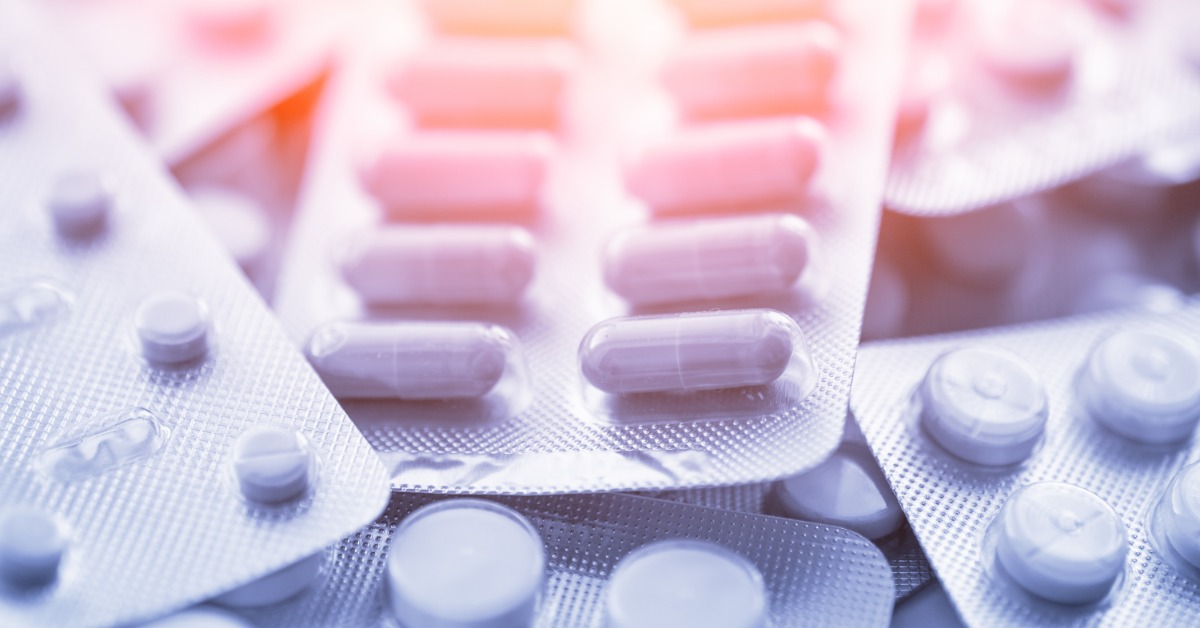 A close-up of a pile of blister packs. The medication in the sleeves is oval, round, and oblong in shape.